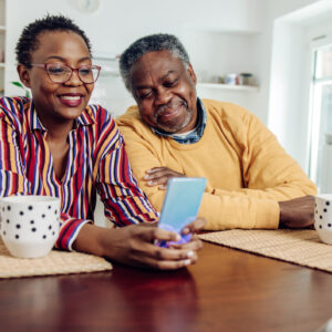 African American senior couple using a smartphone at home.